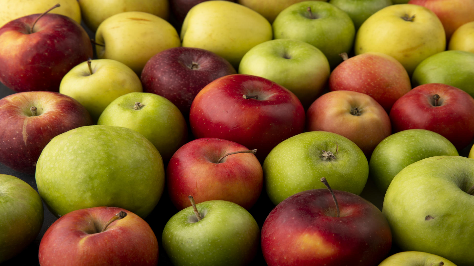 side view apple mix green yellow and red apples on black background